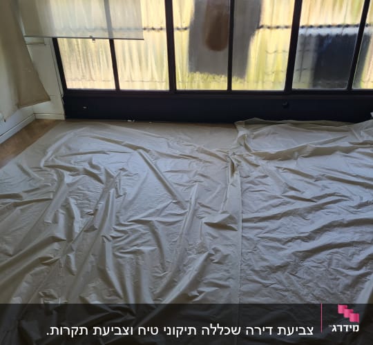 יריעות ניילון פרושות על הרצפה לקראת צביעה